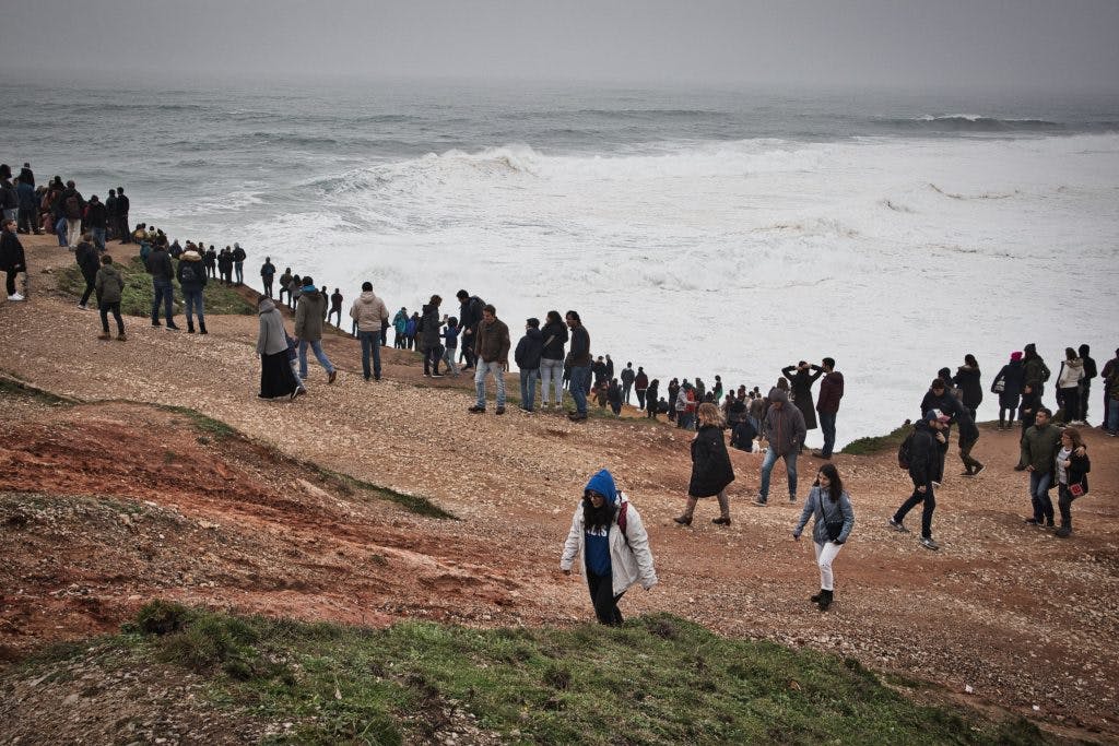groups of people watching big waves in nazare