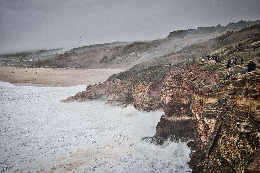 huge waves in nazare hitting the cliffs during a storm