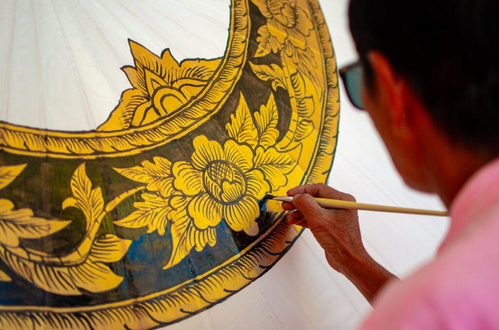 A man painting a big umbrella in yellow, Bo Sang, Thailand. 
