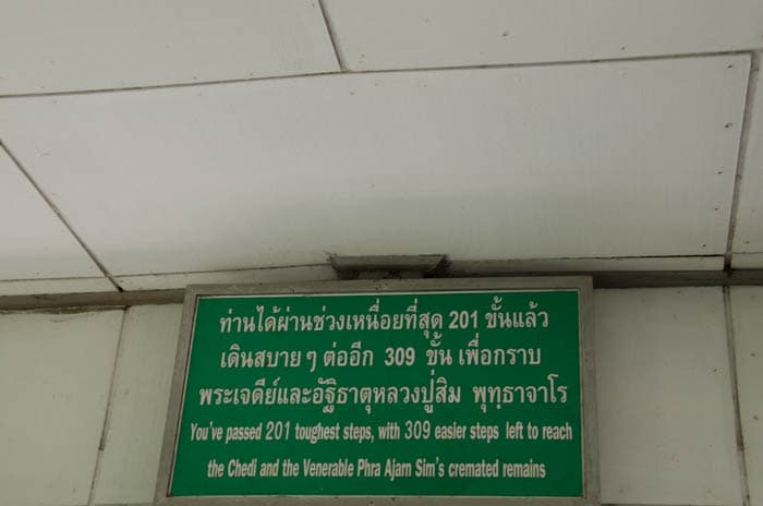 a green sign with white letters with a buddhist quote at chiang dao cave, thailand 