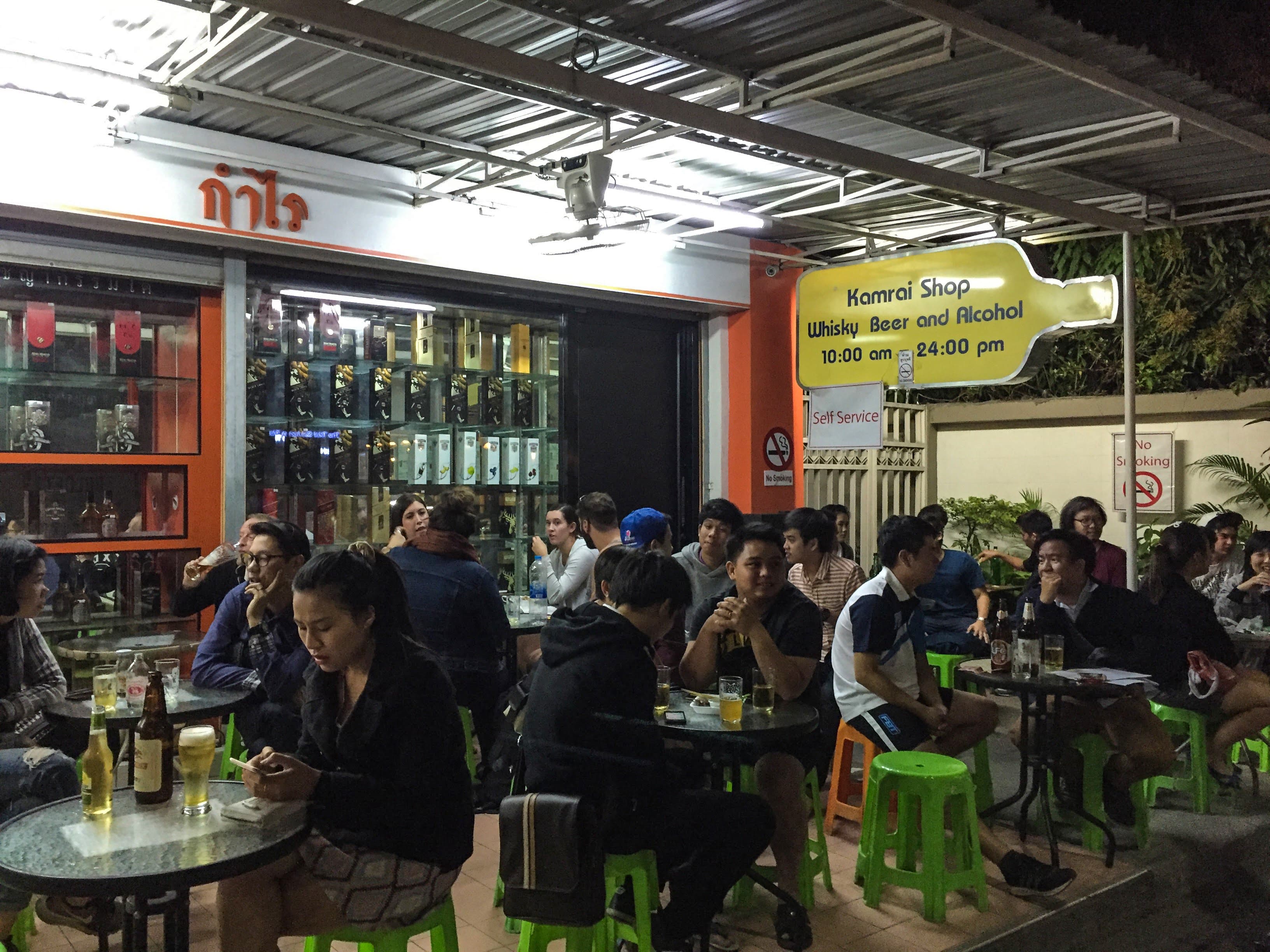 travel healthy - people sitting in a bar in thailand at tiny plastic tables. 