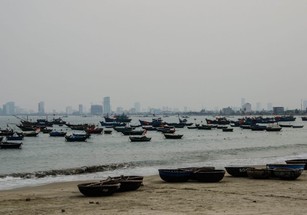 A lot of boats float on the river in Da Nang, vietnam. Behind them you can see the city. 