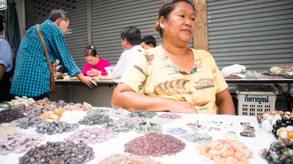 a thai seller of precious stones in chanthaburi, thailand sitting at a table