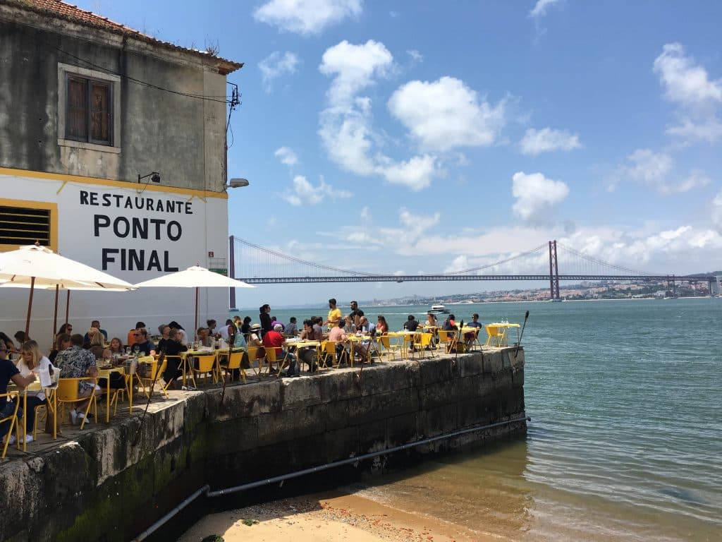 people sitting at tables under white umbrellas in ponto final in almada