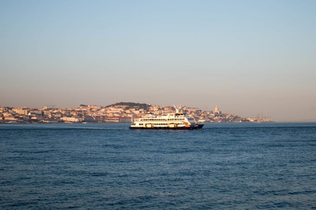 a ferry in lisbon crosses the river at sunset