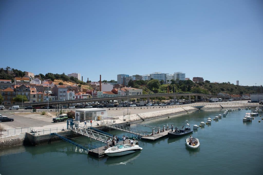 anchored boats in setubal harbour with buildings behind them