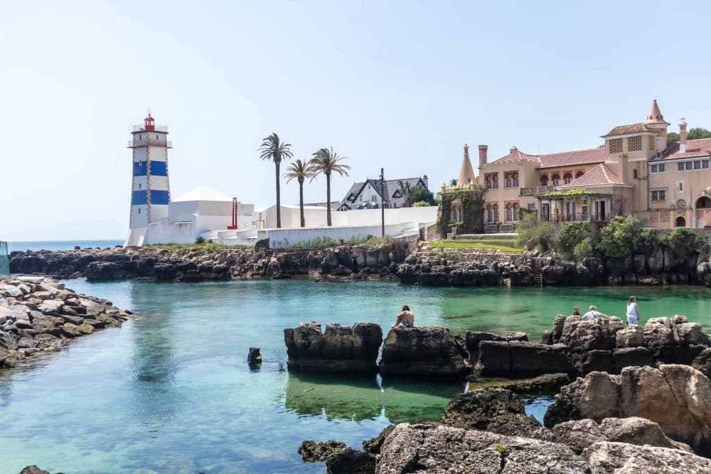latarnia w cascais z blekitna woda i skalami 
