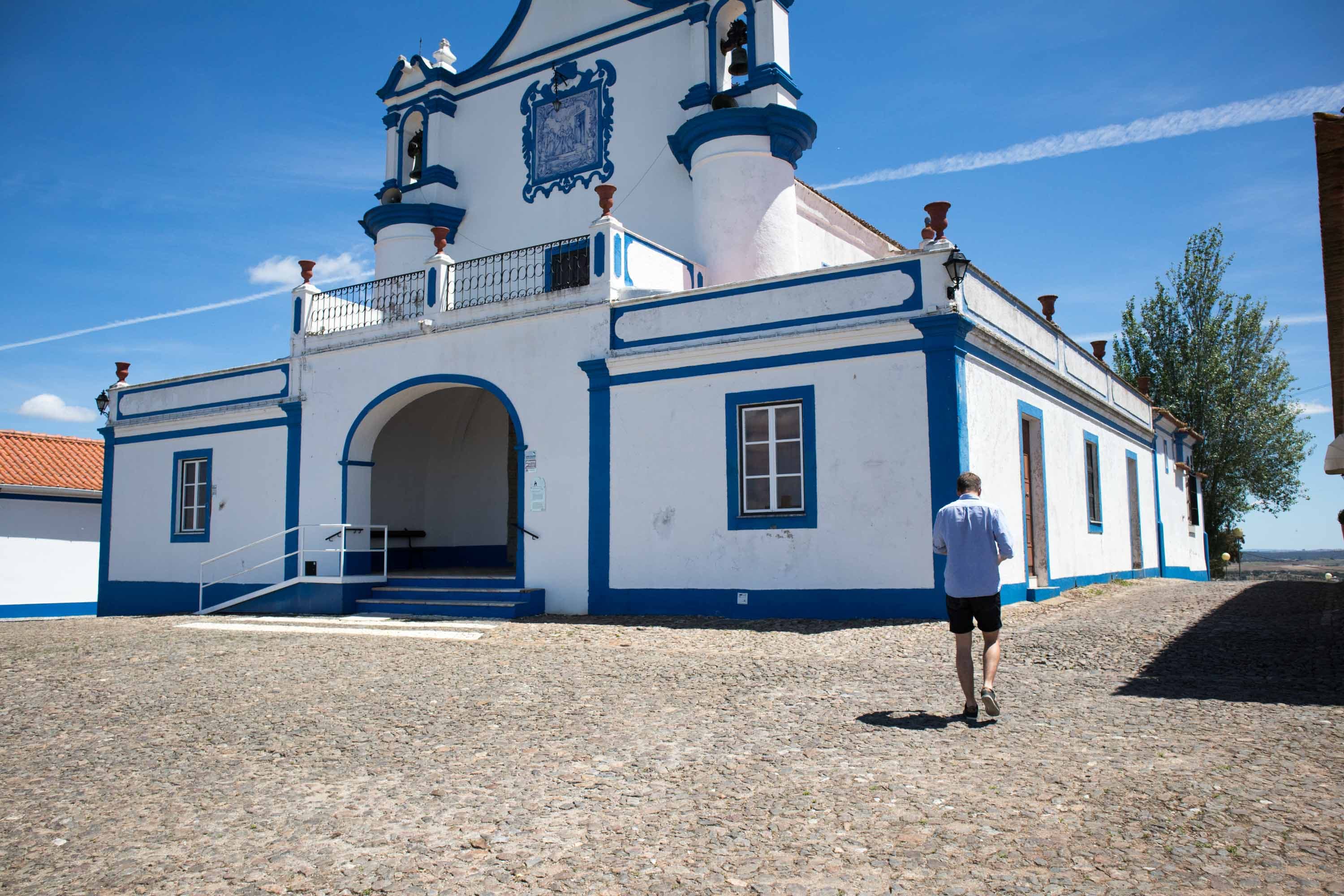 mezczyzna idzie przy niebieskim kosciele na wzgorzu w alentejo