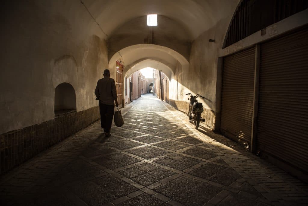 mężczyzna idzie wąską uliczką w yazd, w iranie.