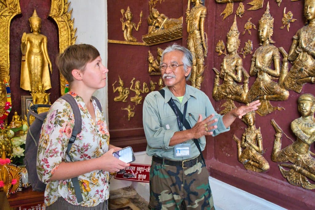 a Thai man showing a foreign woman a stucco in a temple in nakhon si thammarat 