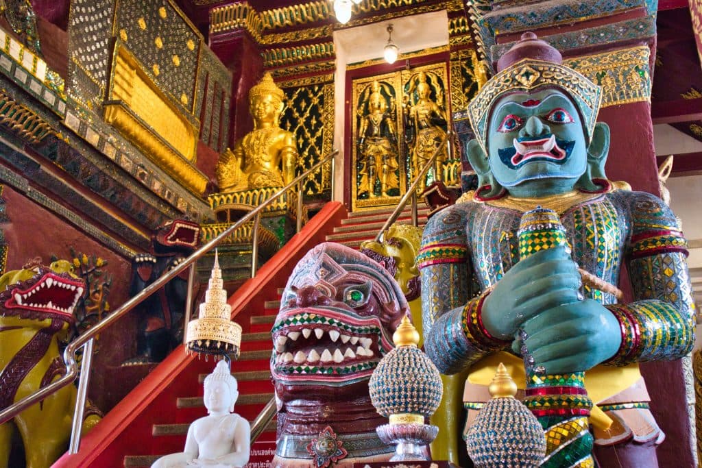 a giant demon statue guarding the entrance to the chedi in nakhon si thammarat temple