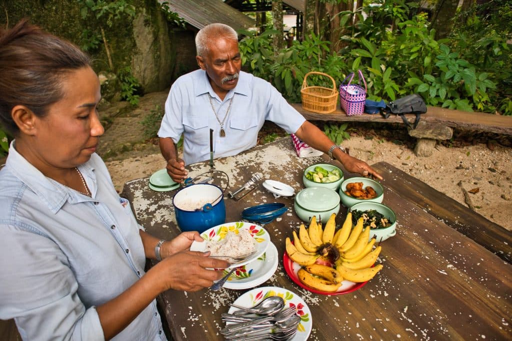 A Thai woman and a Thai man are preparing a picnic in a forest. 