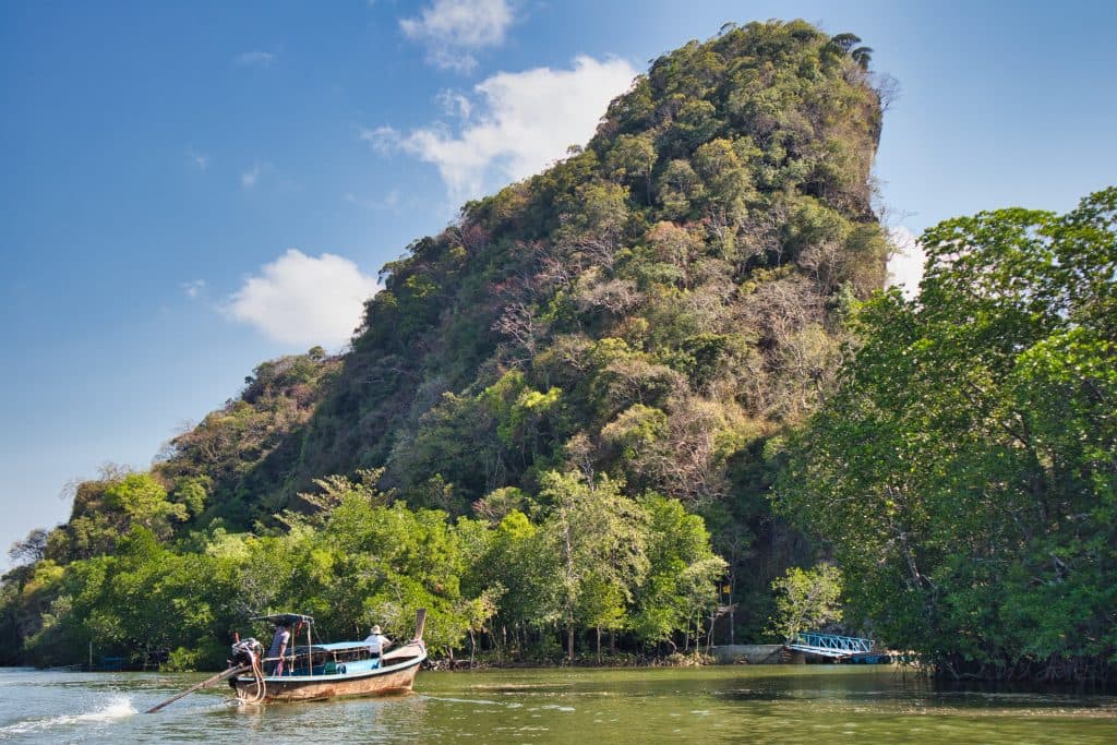 a long tail boat sails among the rocks in krabi province