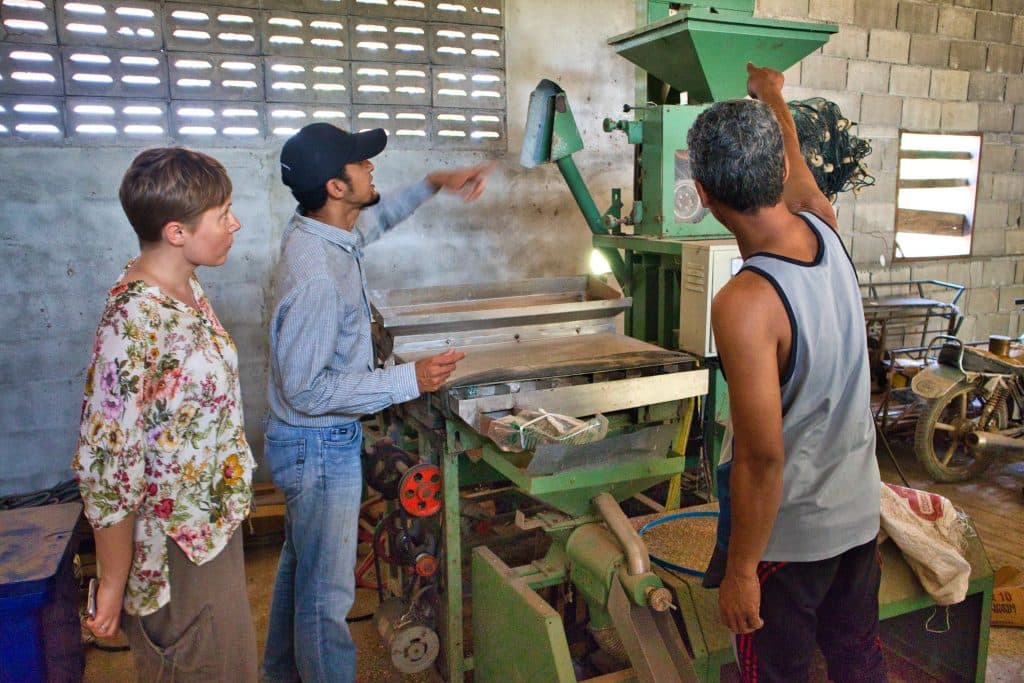 two thai men show a foreign woman old rice making tools in koh klang thailand.  