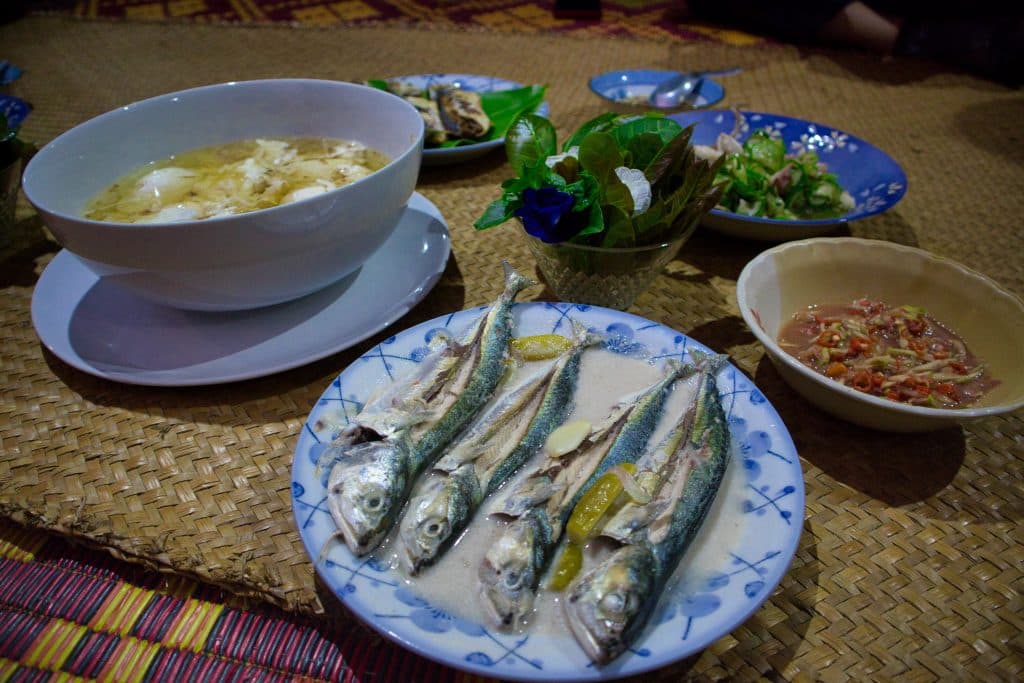 Five plats with soup, fish and chilli sauce set up on a bamboo matt. 