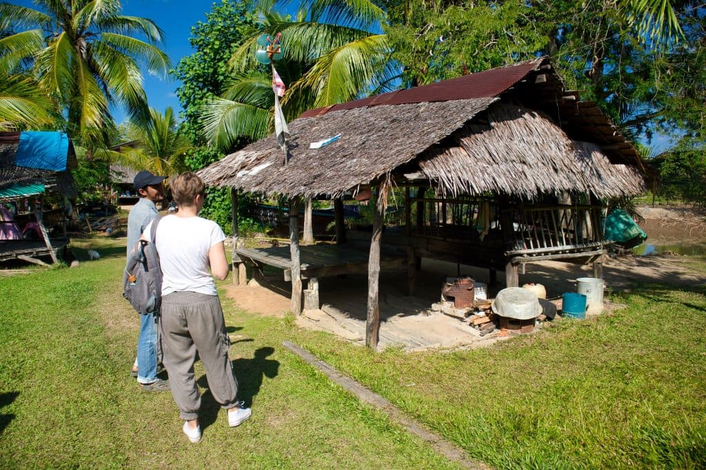 a man and a woman standing next to a small bamboo hut on koh klang, thailand. 