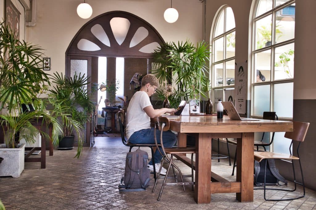 a digital nomad woman sitting in a cafe in chiang mai typing on her laptop
