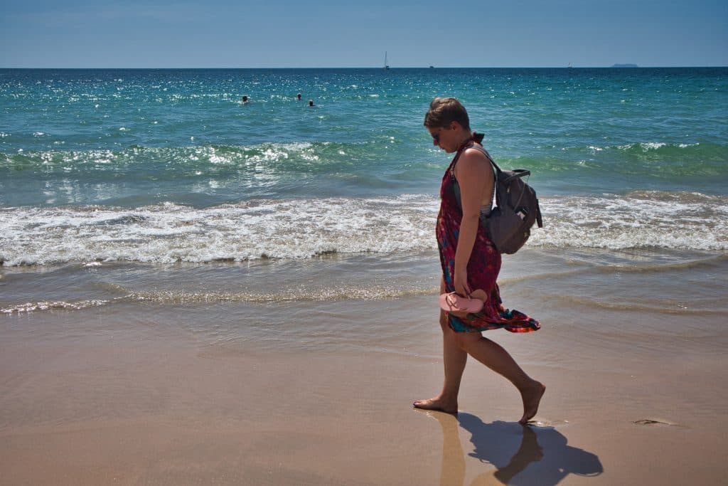 W woman in a colourful sarong walks down the beach in koh lanta, thailand. 