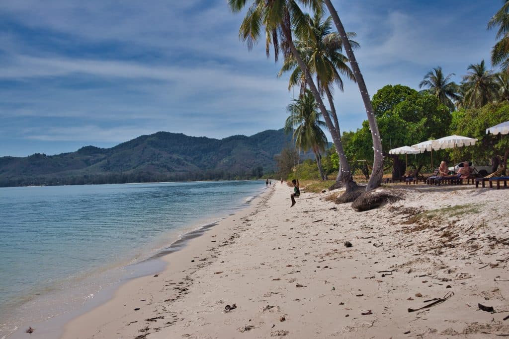 A beach with white sand, a swing and some parasols in koh yao yai, thailand. 