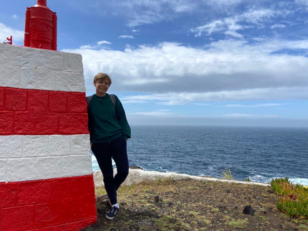 Dziewczyna stoi pod latarnią morską na wyspie terceira. 