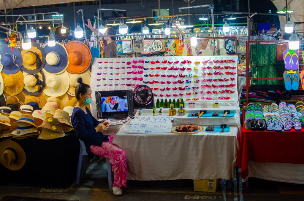 Tajka siedzi przy stoisku z pamiątkami na night bazzar, chiang mai.