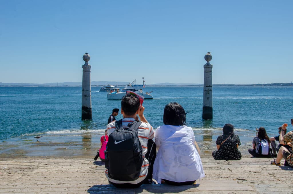 Two columns seen from the shore. A couple looking at two columns in Lisbon. 