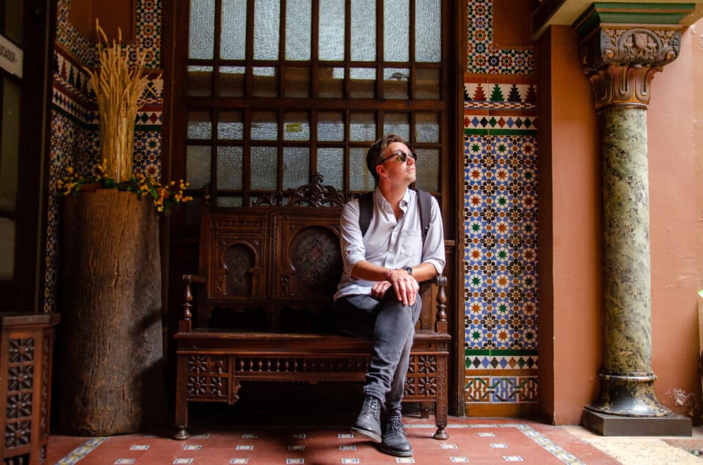 a man sitting on a bench near tiled wall, Lisbon. 