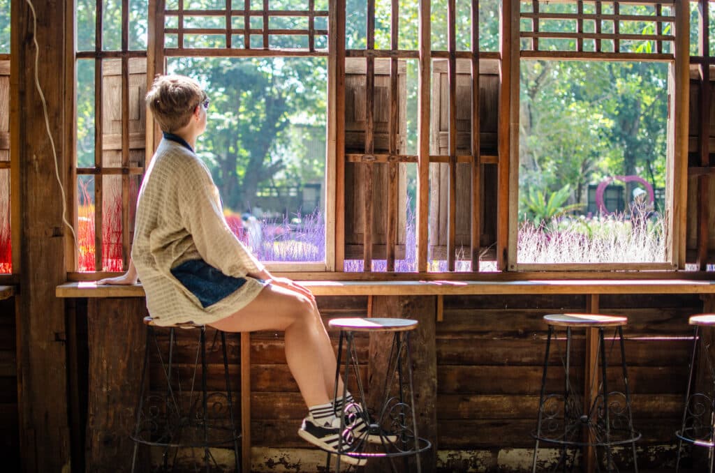 A woman sitting at a wooden window. 