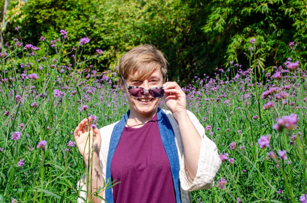 A woman in a field with sunglasses on.