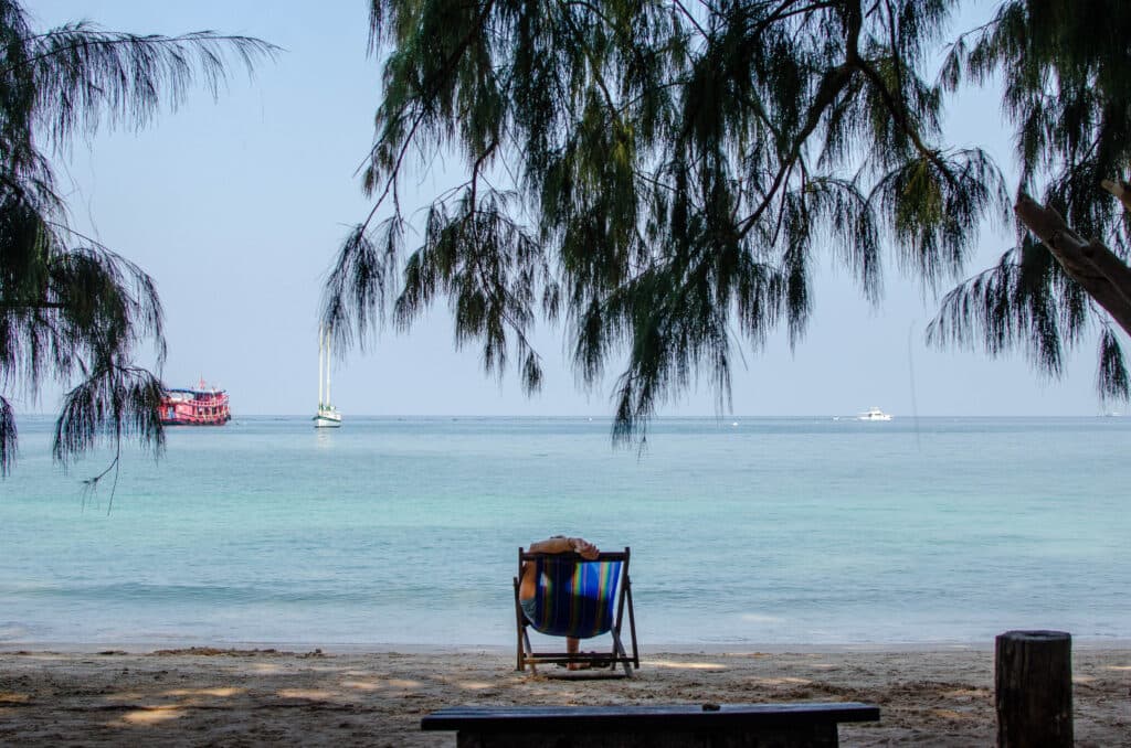 Turysta leży na leżaku na Koh Tao i patrzy się w wodę i statki. 