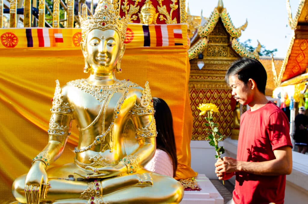Posąg Buddy na Doi Suthep. Ludzie chodzą wokół z kwiatem lotosu. 