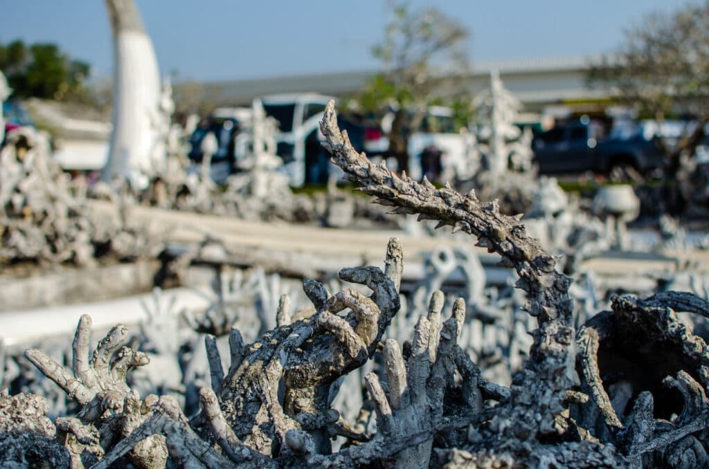 Sculptures of hands reaching out to the entrance of the temple in chiang rai.