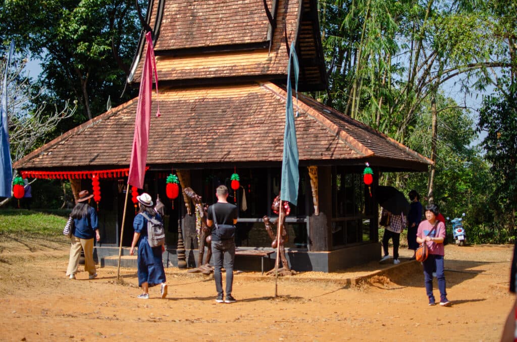 A small black buidling with lanterns on it.