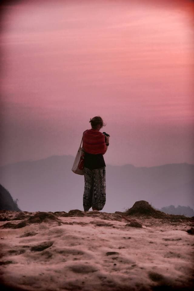 a woman with a camera standing on an edge of a mountain in thailand