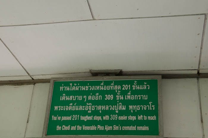a green sign with white letters with a buddhist quote at chiang dao cave, thailand 