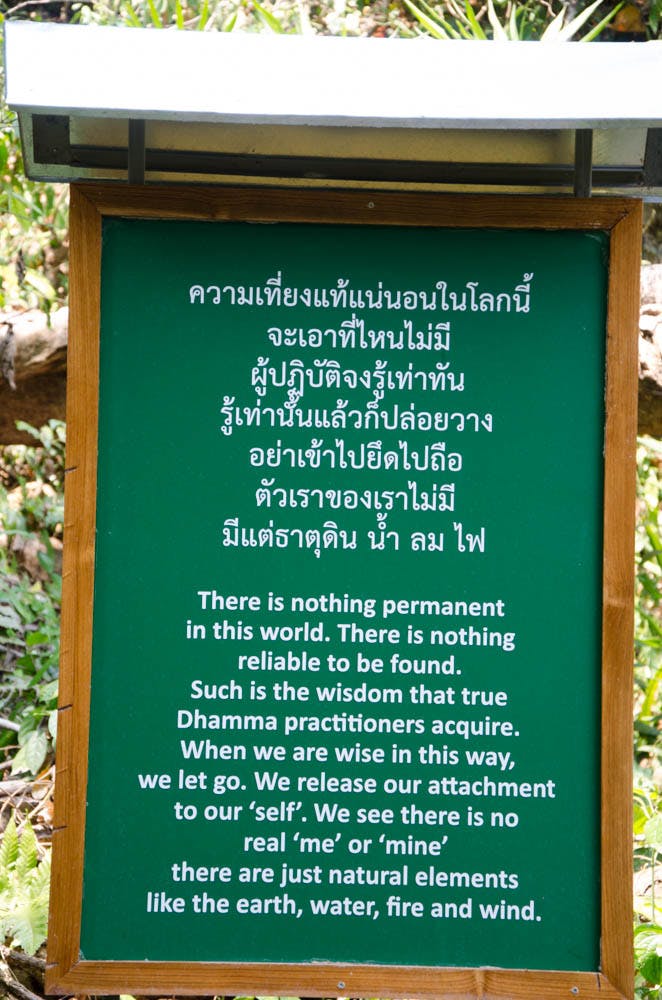 a green sign with white letters at wat po ploy, chiang dao, thailand 