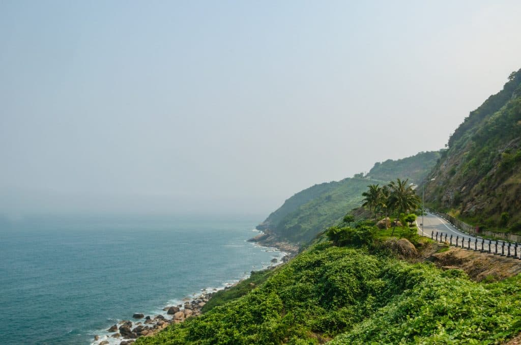 A view over Son Tra Peninsula with winding roads and forests. There is water at the bottom of the road.