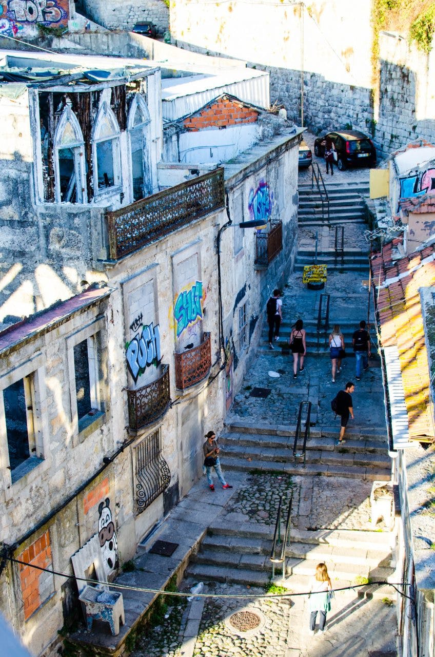 a street in porto. narrow stairs among old houses lead up the hill. people walk up the stairs in porto. 