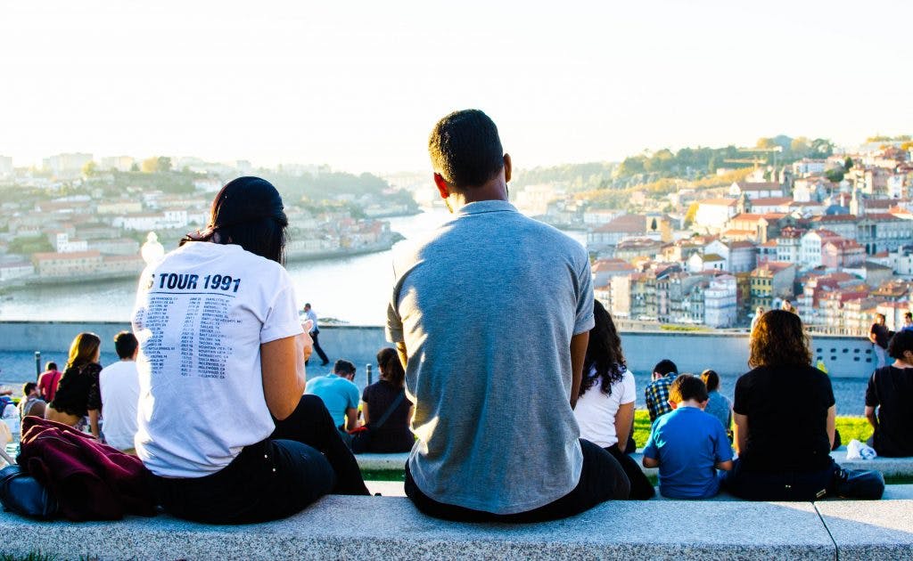 Ludzie siedzą na zachodzie słońca nad rzeką w Porto. 