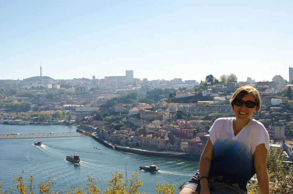 one day in porto. Joanna sits at a viewpoint in porto overlooking the river and the city. 