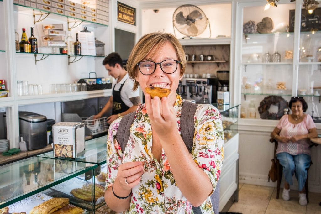 girl holiding a pastel de nata in a bakery in lisbon 