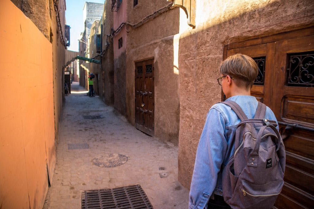 a girl in a jeans jackets walks in an alley in marrakesh