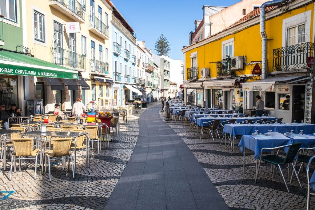empty tables wait for customers on a sunny day in cacilhas lisbon