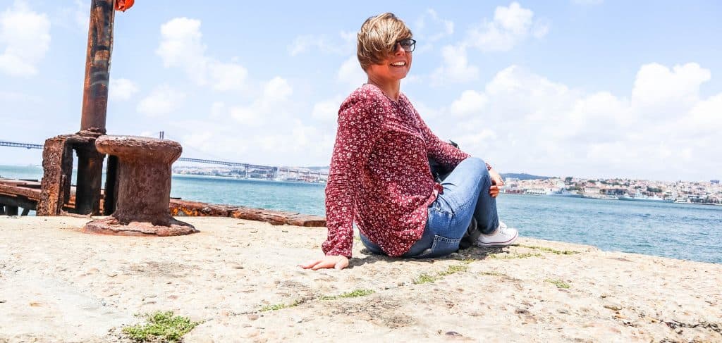 a girl sits on a shore in almada and laughs