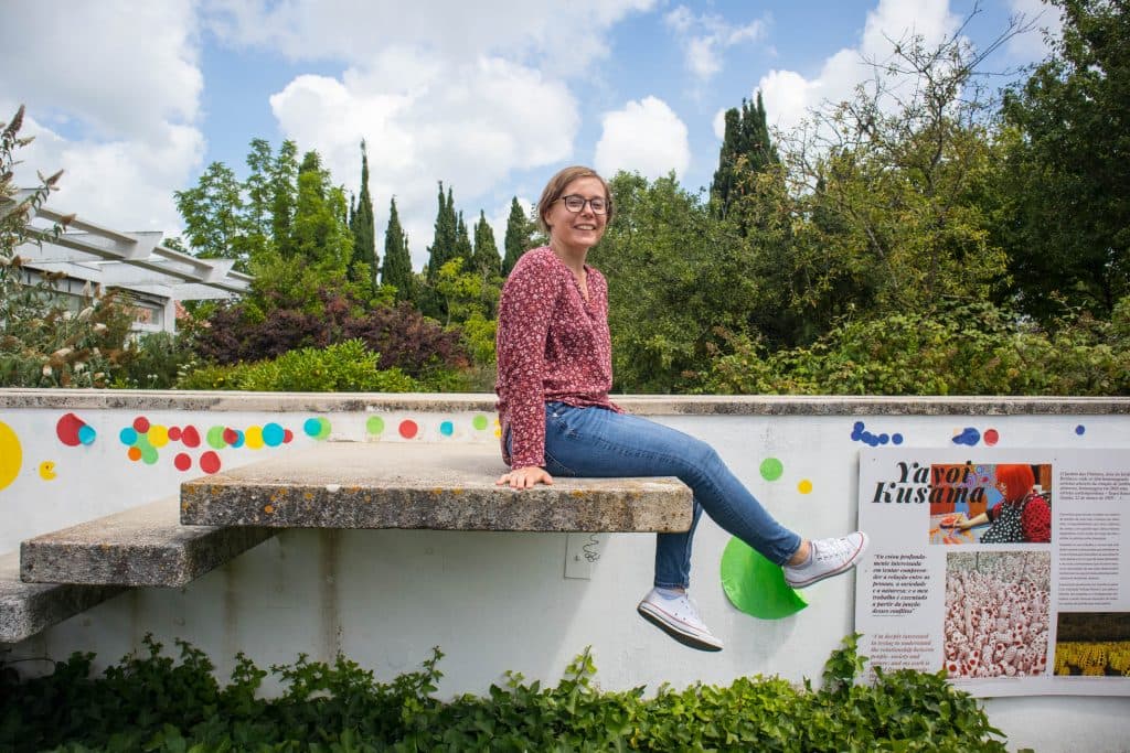 a girl sits on a wall in a botanical garden in almada portugal lisbon