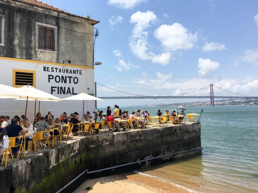 ludzie siedza przy solikach ponto final w lizbonie