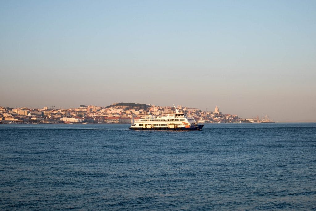a ferry in lisbon crosses the river at sunset
