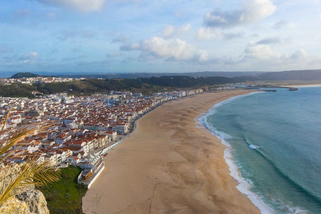 a beach in nazare portugal seen from a top of a cliff 
