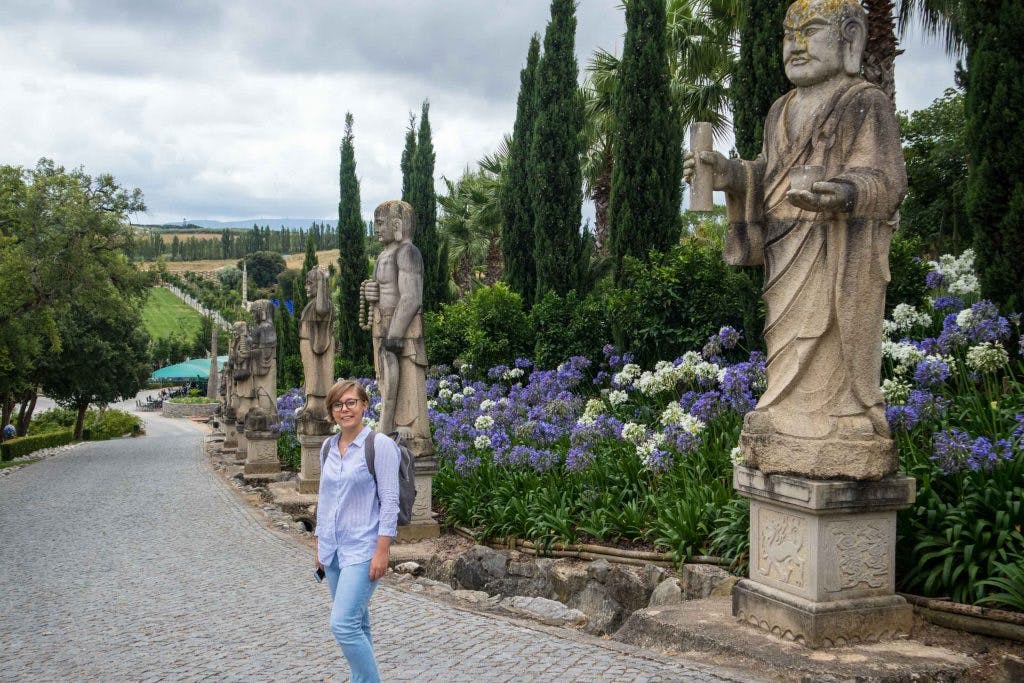 a girl standing among flowers in buddha garden in portugal 