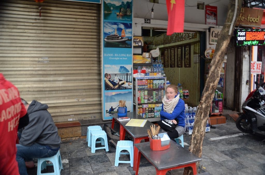 a girl in a blue jumper sits at a table in a vietnamese restaurant